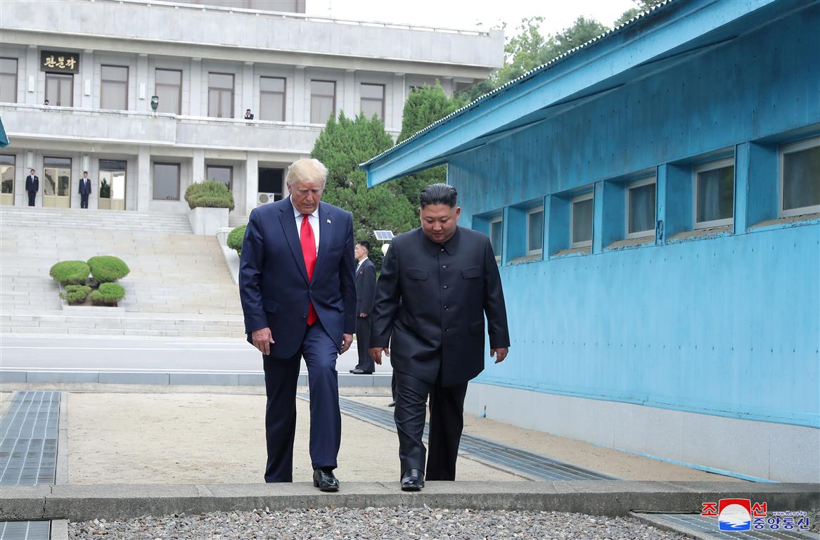 US President Donald Trump (L) and North Korean leader Kim Jong Un cross over a military...