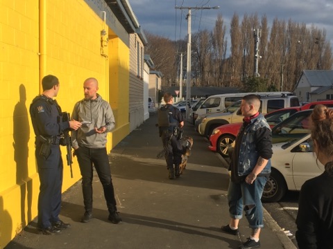 An armed police officer takes statements outside the Dunedin Art School. Photo: George Block