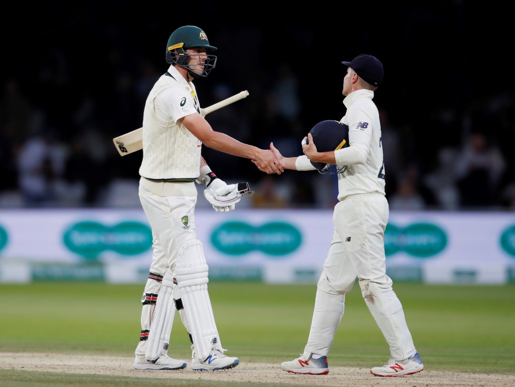 Australia's Pat Cummins and England's Rory Burns shake hands at the end of play as the second...