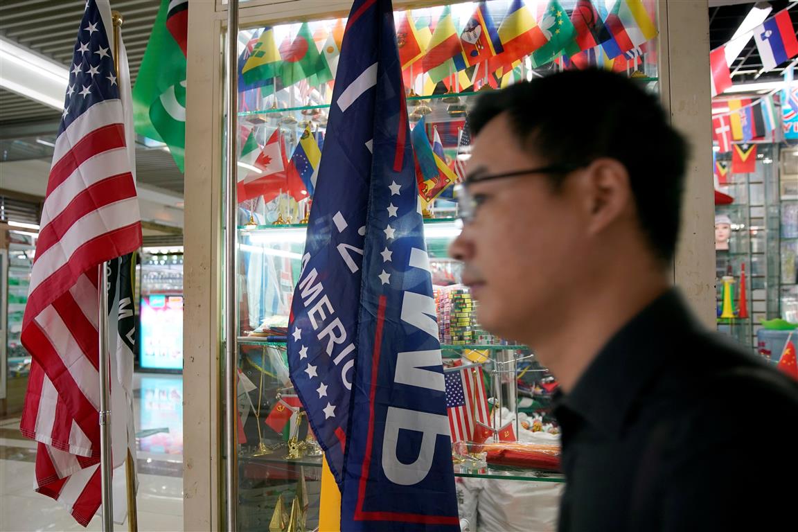 The US flag  and a 2020 re-election campaign flag and are seen in a stall at the Yiwu Wholesale...