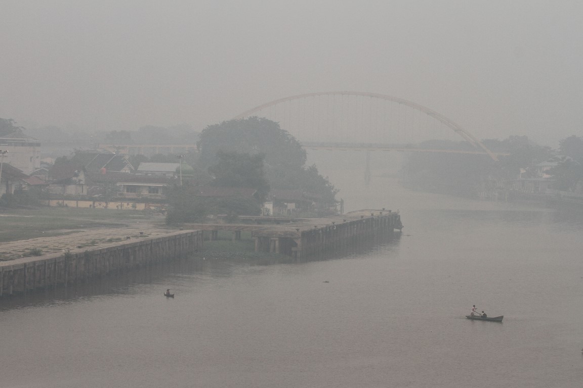 People cross a smog-covered river in Pekanbaru, Riau province, Indonesia. Photo: Antara Foto/Rony...