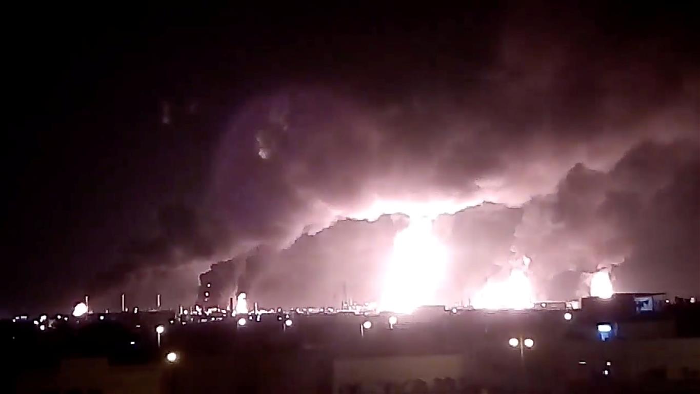 Fires burn in the distance after the strike on Saudi company Aramco's oil processing facilities...