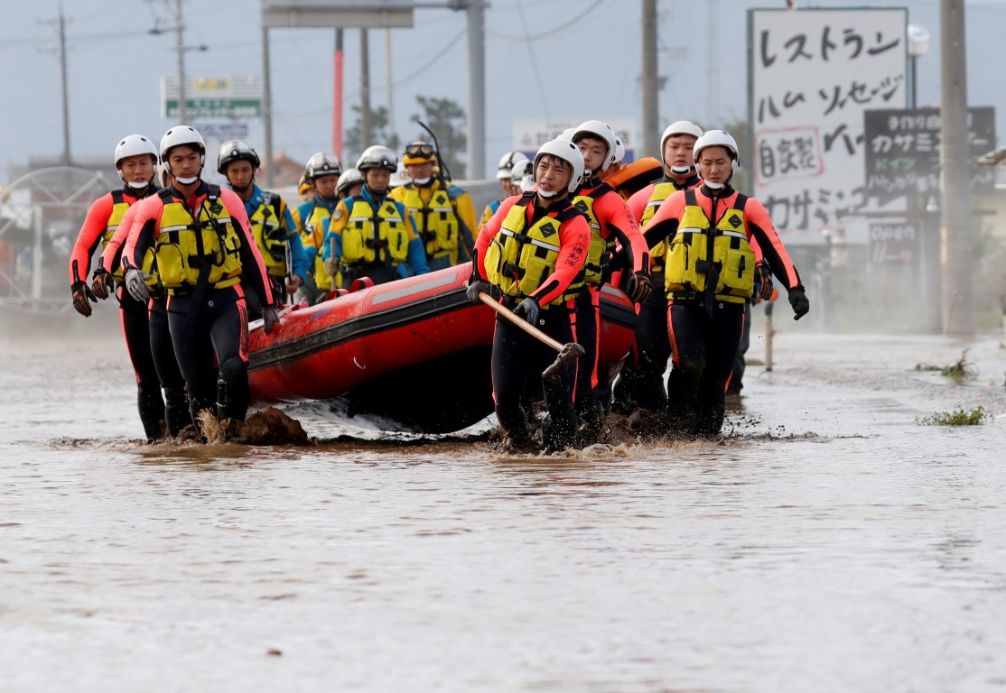 Rescue workers in Nagano Prefecture carry a rubber dinghy as they search a flooded area in the...