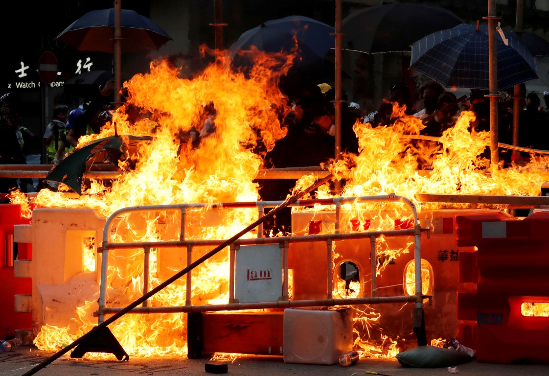 Protesters set fire at a barricade as policemen advance during an anti-government protest in Hong...