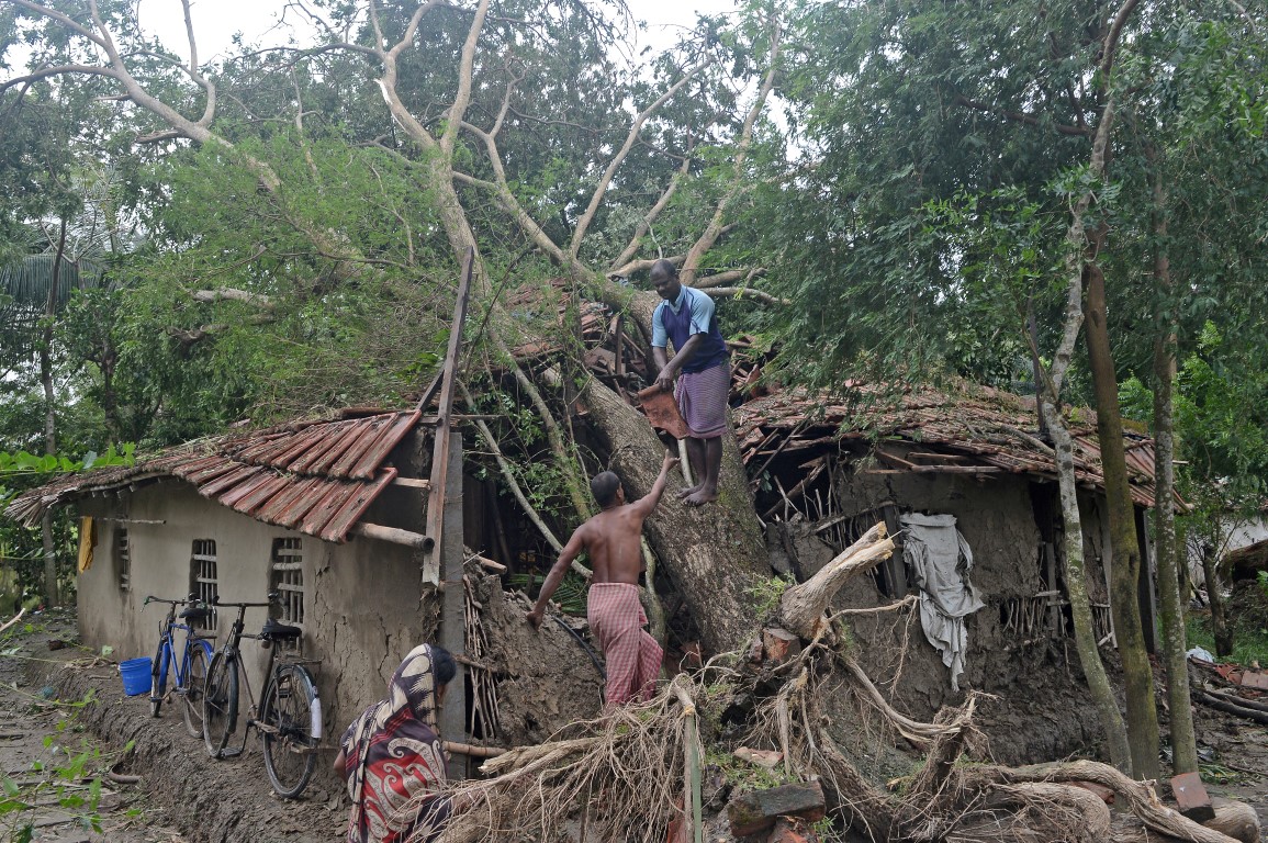 Men try to clear debris from their damaged house after Cyclone Bulbul hit the area in Namkhana,...