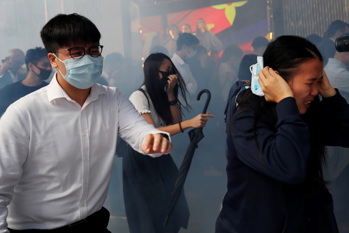 People run away from tear gas as they attend a flash mob anti-government protest at the financial...