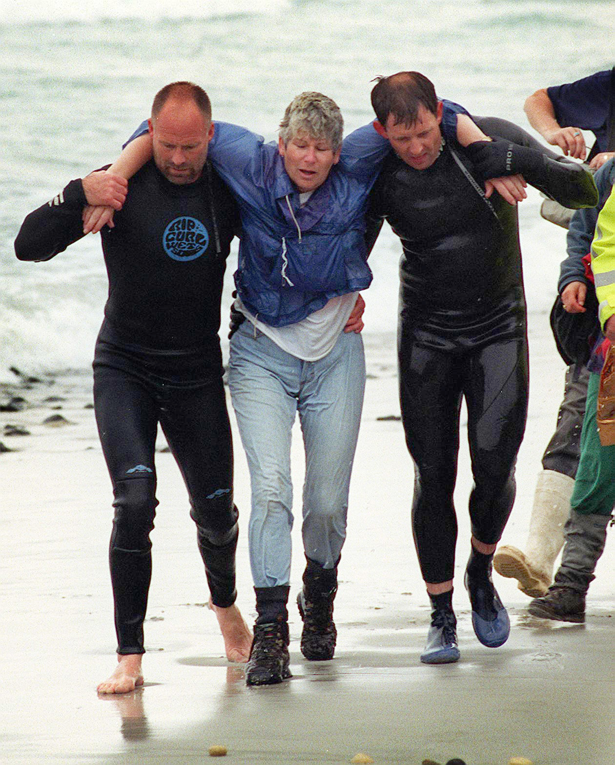 Margaret Dodds is helped to shore by rescuers Neil Price (left) and Senior Sergeant Brian Benn....