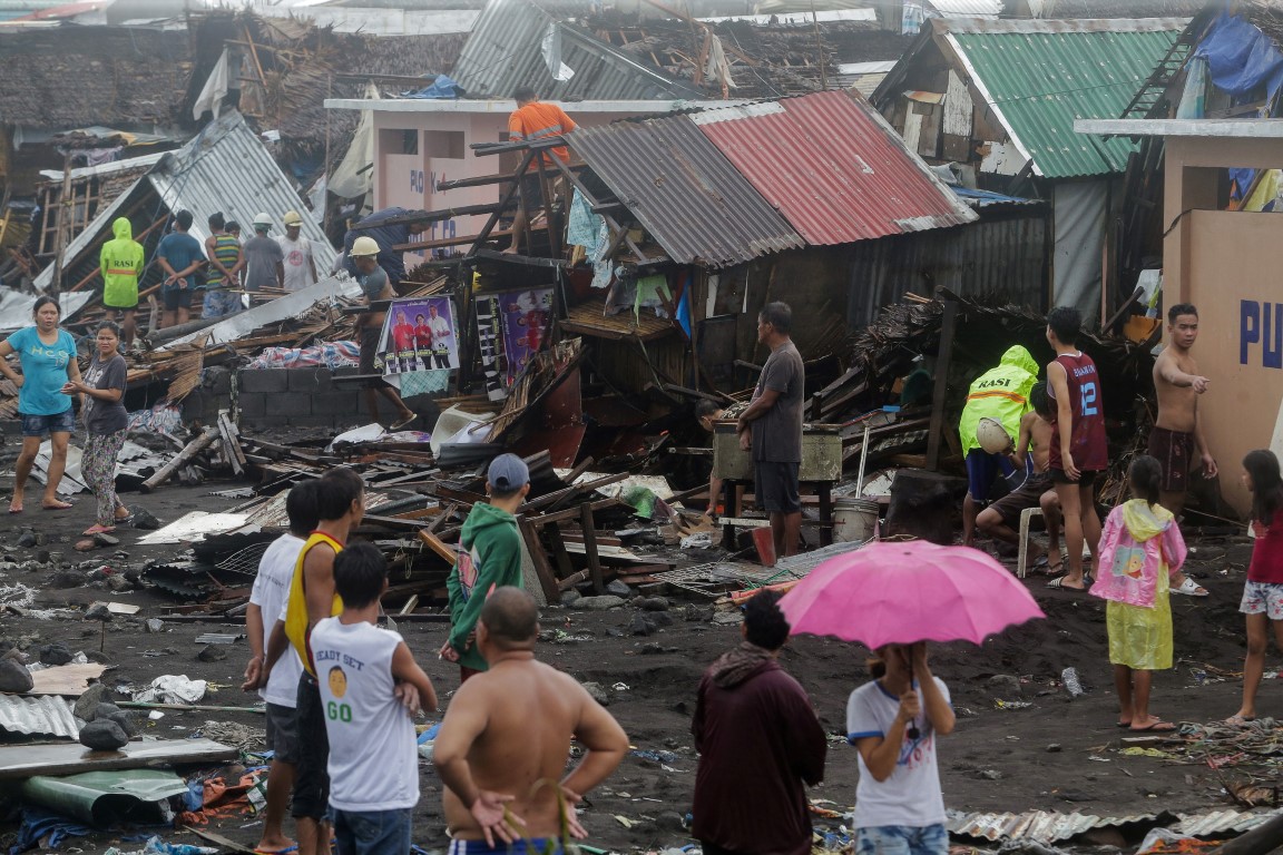 Residents stand among their damaged houses after Typhoon Kammuri hit Legazpi City, Albay, in the...