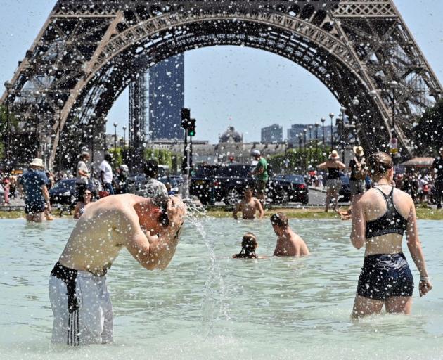 People cool down in the fountains of Trocadero near the Eiffel Tower in Paris in June 2019. ...