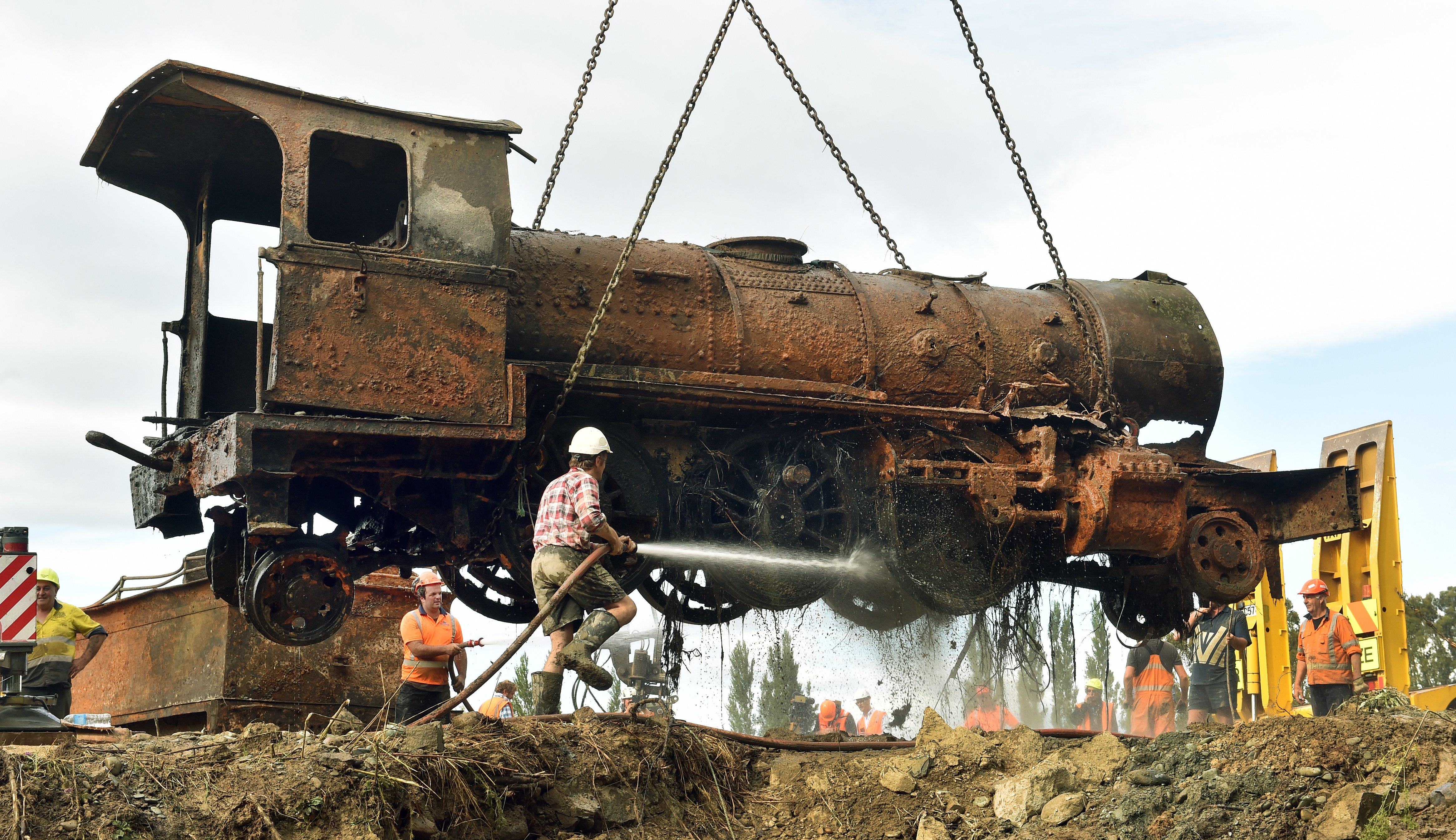 Project Steam member Clark McCarthy, of Dunedin, hoses mud off a steam locomotive as it is...