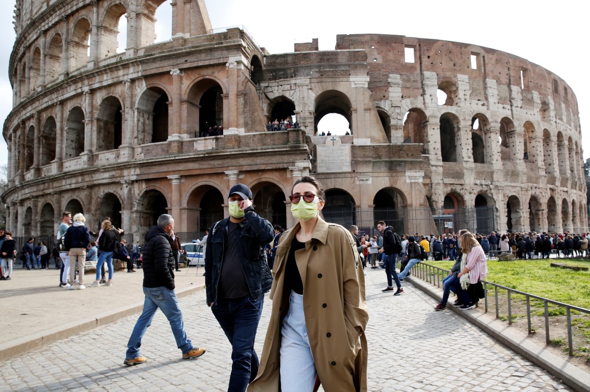 People wearing protective masks walk past the Colosseum in Rome. Photo: Reuters