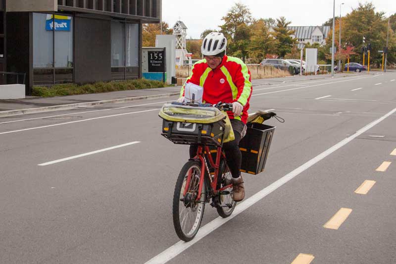 Postie struggling in the strong wind on Kilmore St. Photo: Geoff Sloan