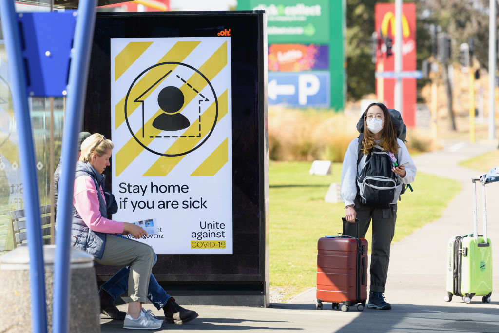 A traveller wearing a protective mask waits for a bus near Christchurch International Airport....