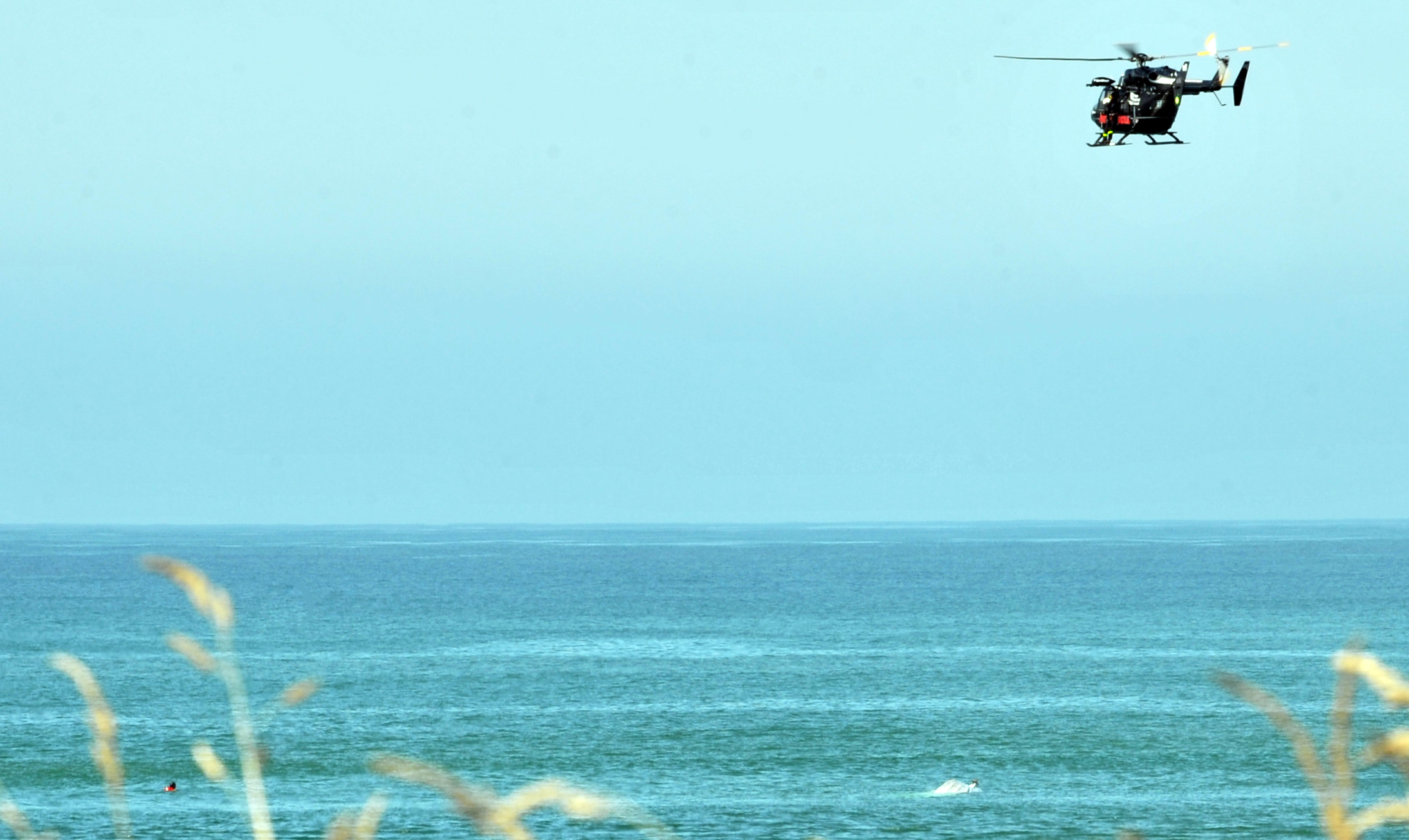 A rescue helicopter prepares to rescue a person from the water (left) this afternoon. Photo:...
