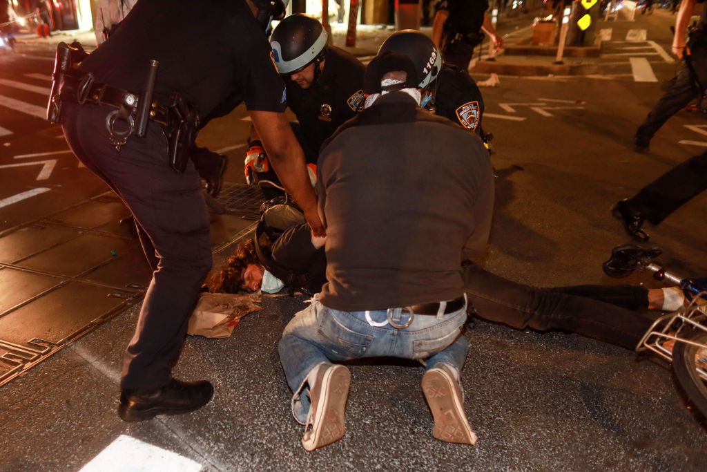 Police officers handcuff a protester after a curfew deadline during a rally in Manhattan...