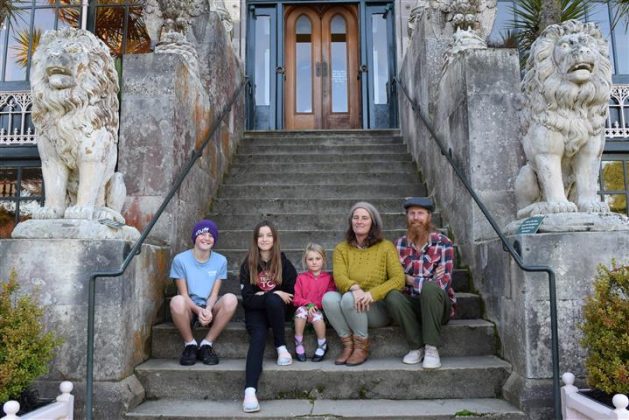 Sitting on the steps of an entrance to Larnach Castle are parents Carmen Howell and Tim Ryan and...