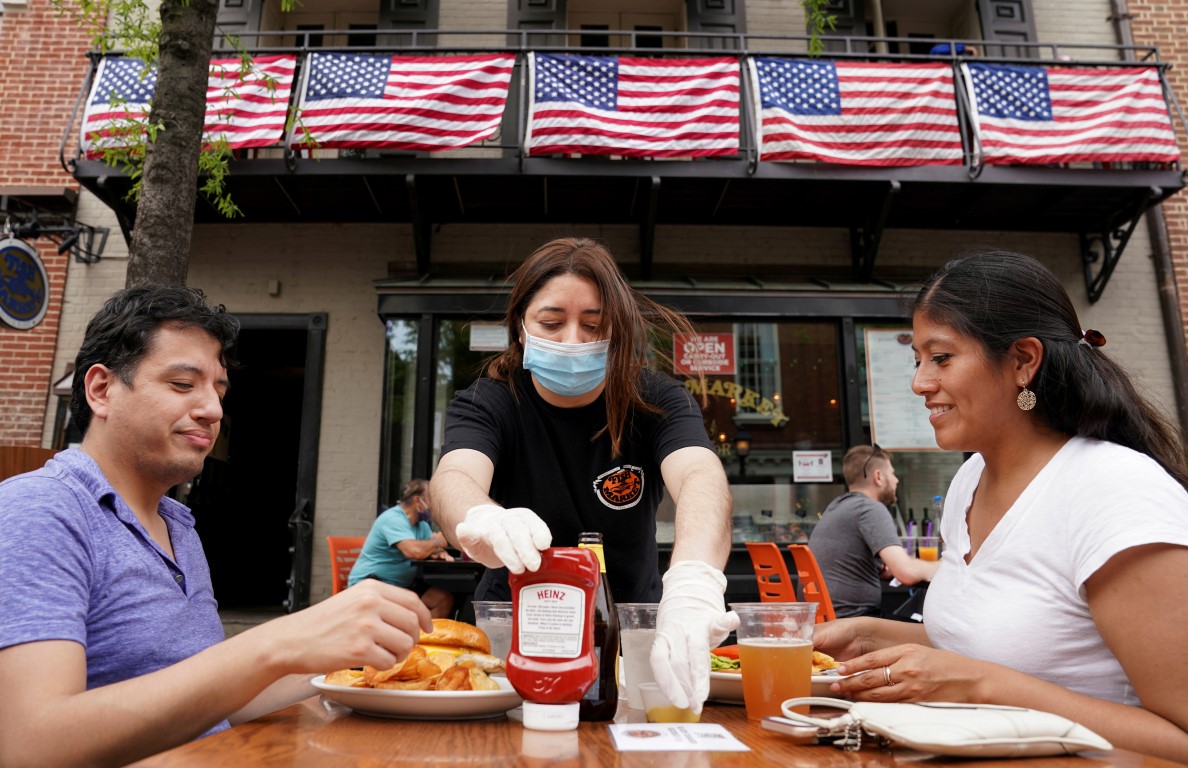 A waitress with a face mask serves diners at a restaurant in Alexandria, Virginia. Photo: Reuters