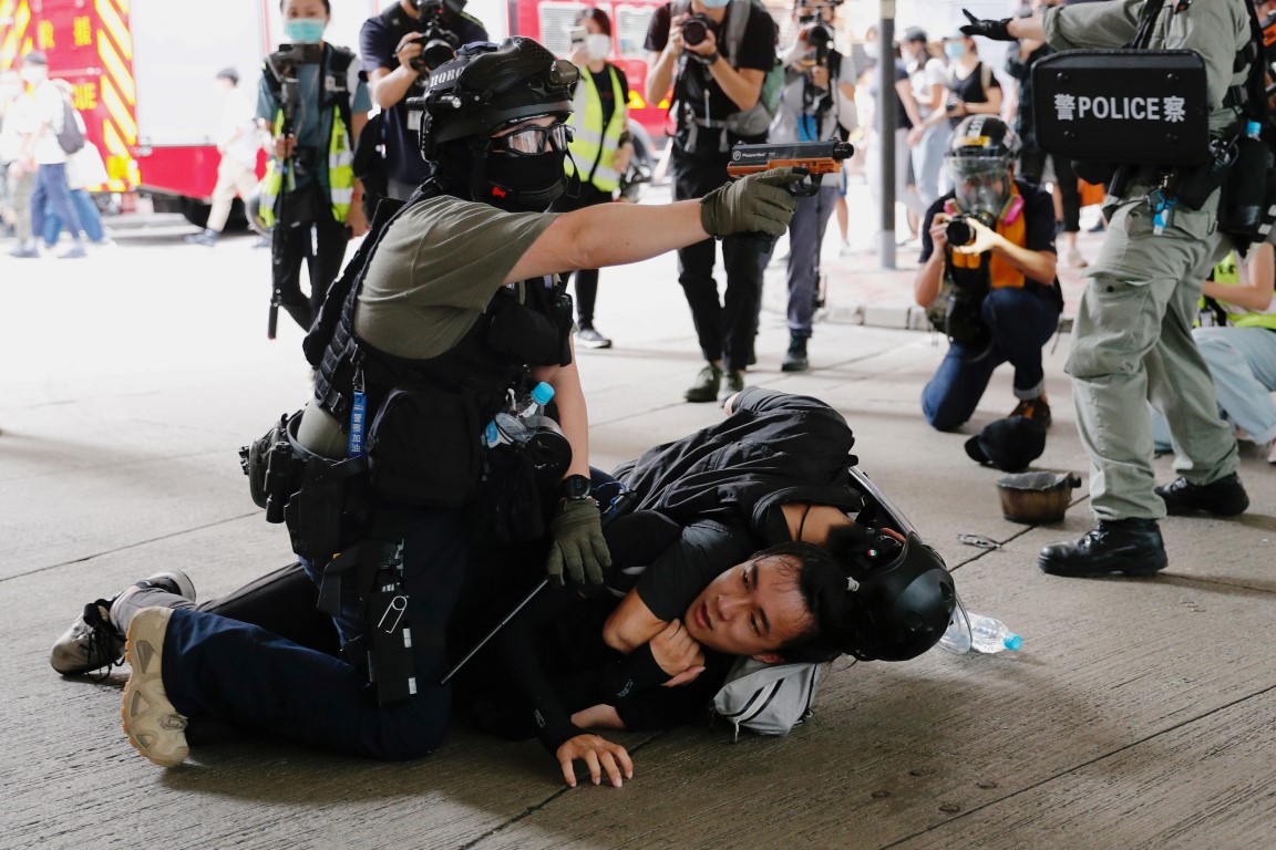 Police officers detain a man during a march against the national security law in Hong Kong. Photo...