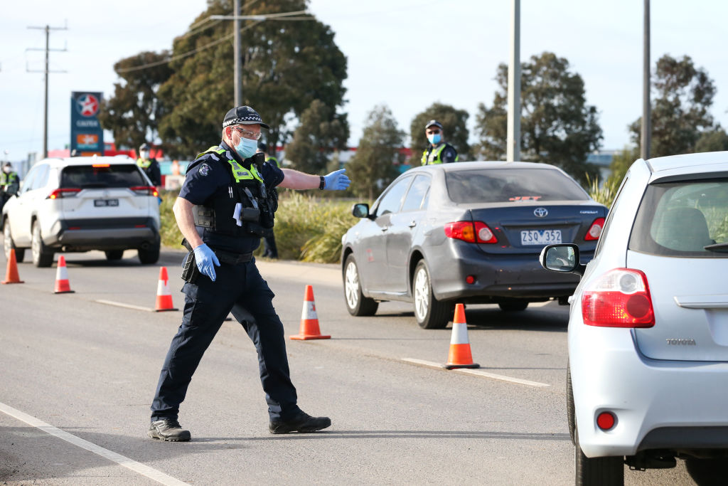 A police officer directs traffic into a checkpoint lane in Melbourne. Photo: Getty 