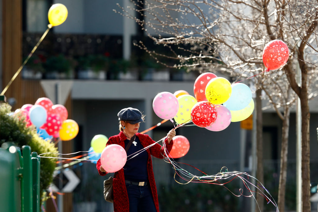 A woman ties balloons on a fence outside a public housing tower in Melbourne. Nine of the city's...