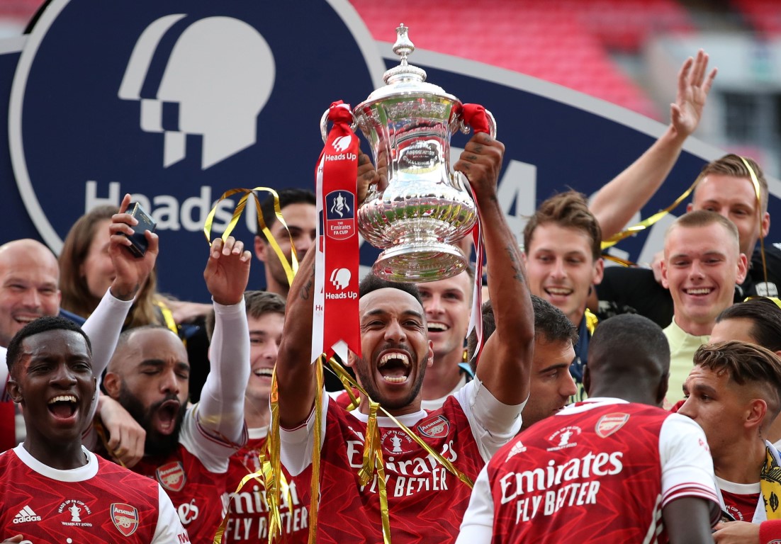 Arsenal skipper Pierre-Emerick Aubameyang lifts the trophy as his teammates celebrate after...