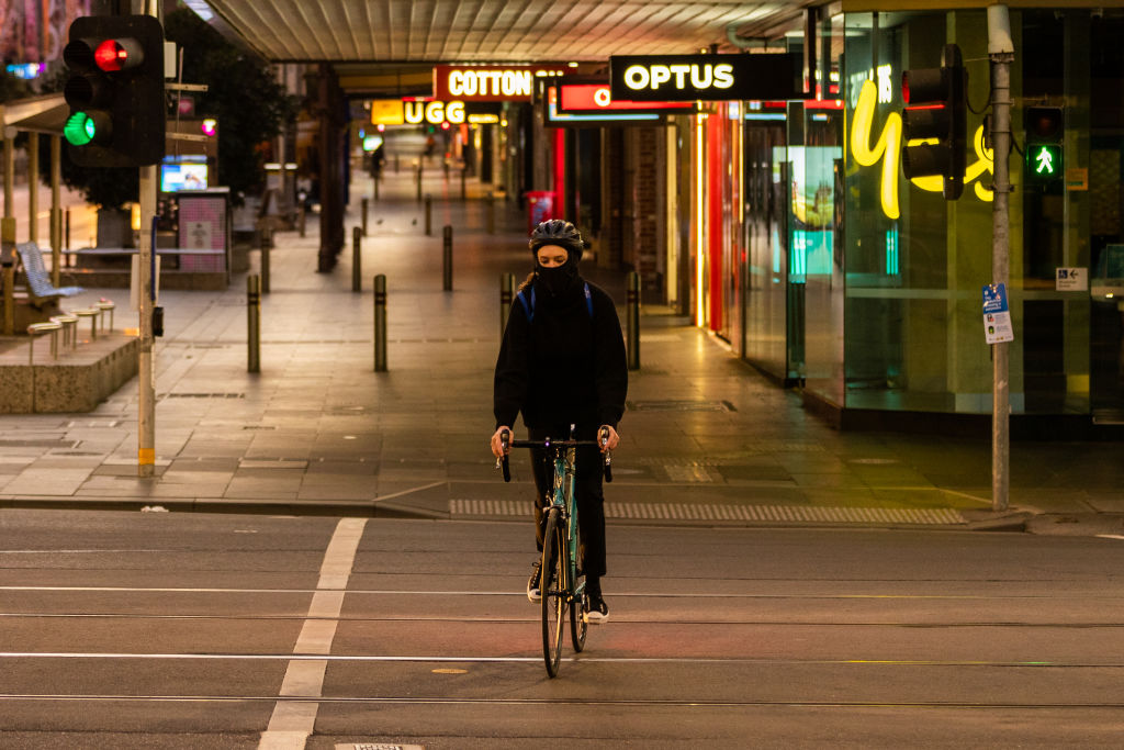 A cyclist crosses a usually busy Bourke St in Melbourne early today. Photo: Getty