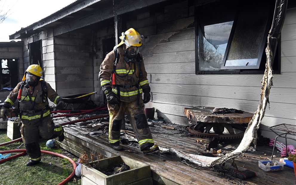 Firefighters walk through the burnt remains of the house near Waikouaiti. Photo: Linda Robertson 