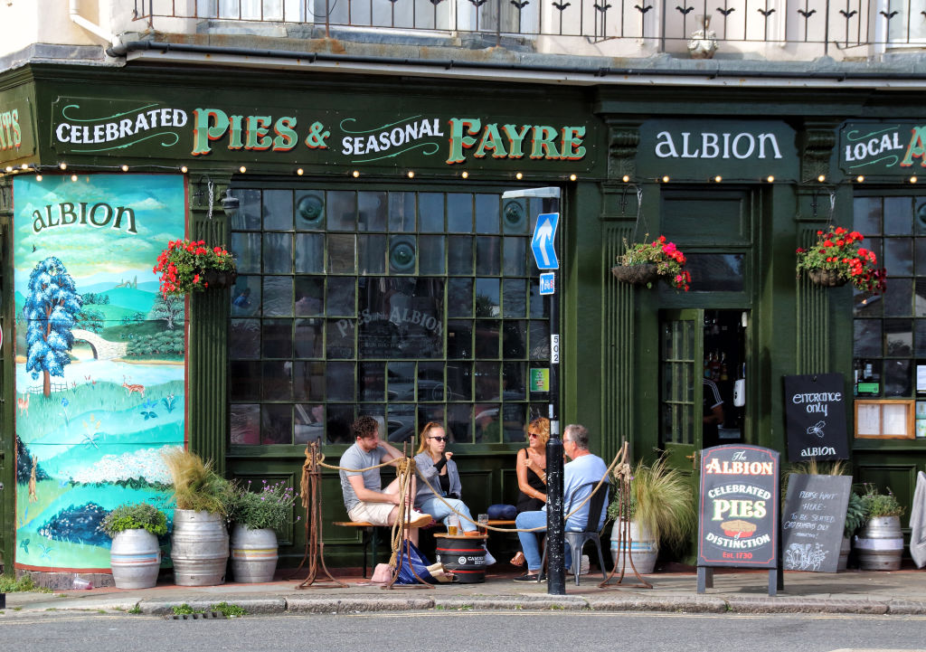 People sit outside a pub in Hastings, England. Photo: Getty Images)