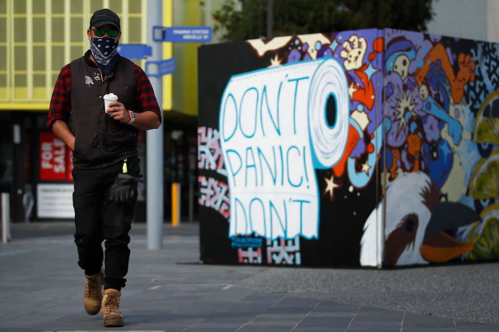 A man in a mask walks past street art in Prahran, in Melbourne. Photo: Getty