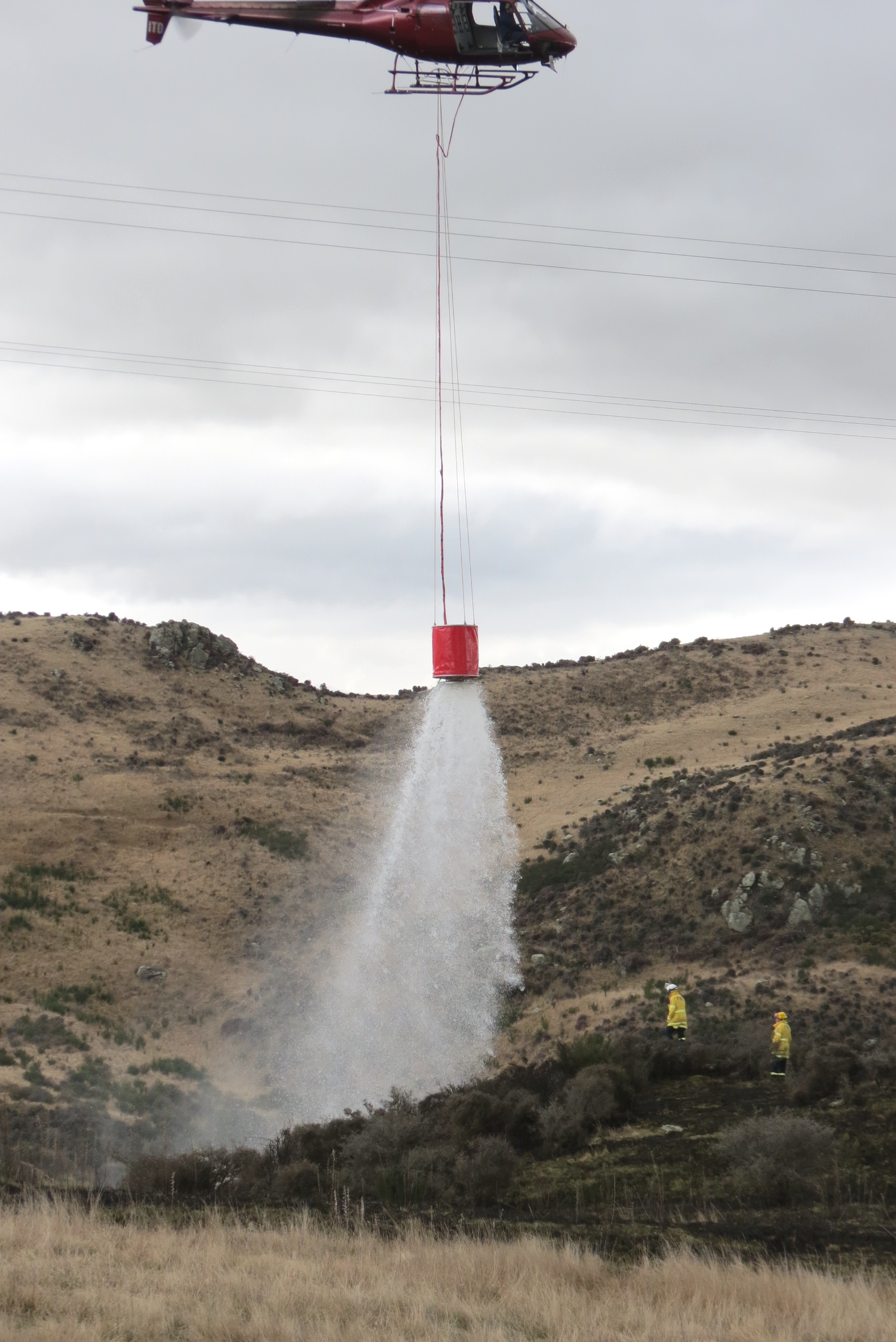 A helicopter helps ground crews extinguish the grass fire near Roxburgh this afternoon. Photo: Yvonne O'Hara