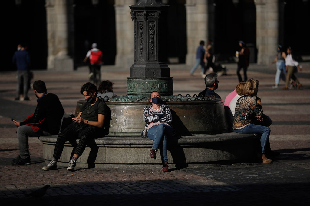 People wear face masks after the Spanish government imposed a 15-day state of emergency in the...