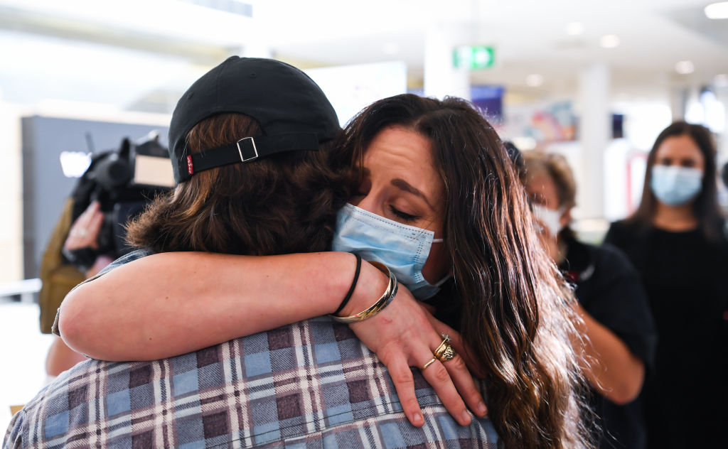 A woman hugs her loved one after arriving in Sydney on the first flight. Photo: Getty