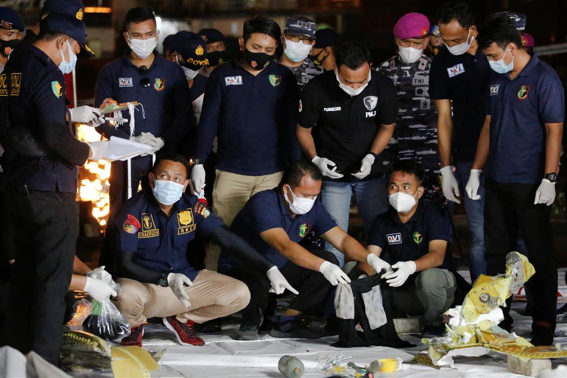 Disaster Victim Identification officers at Jakarta's Tanjung Priok port look through items found...