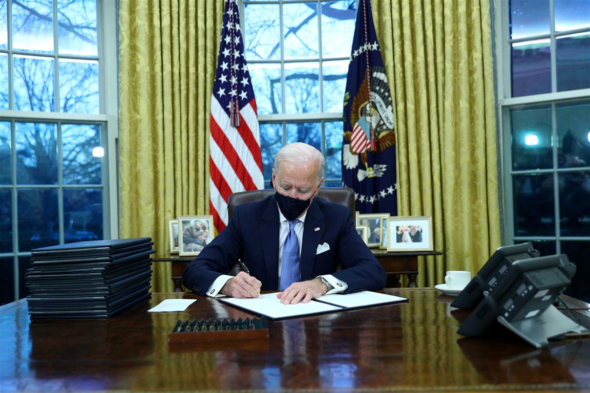 Joe Biden signs executive orders in the Oval Office of the White House in Washington, after his...