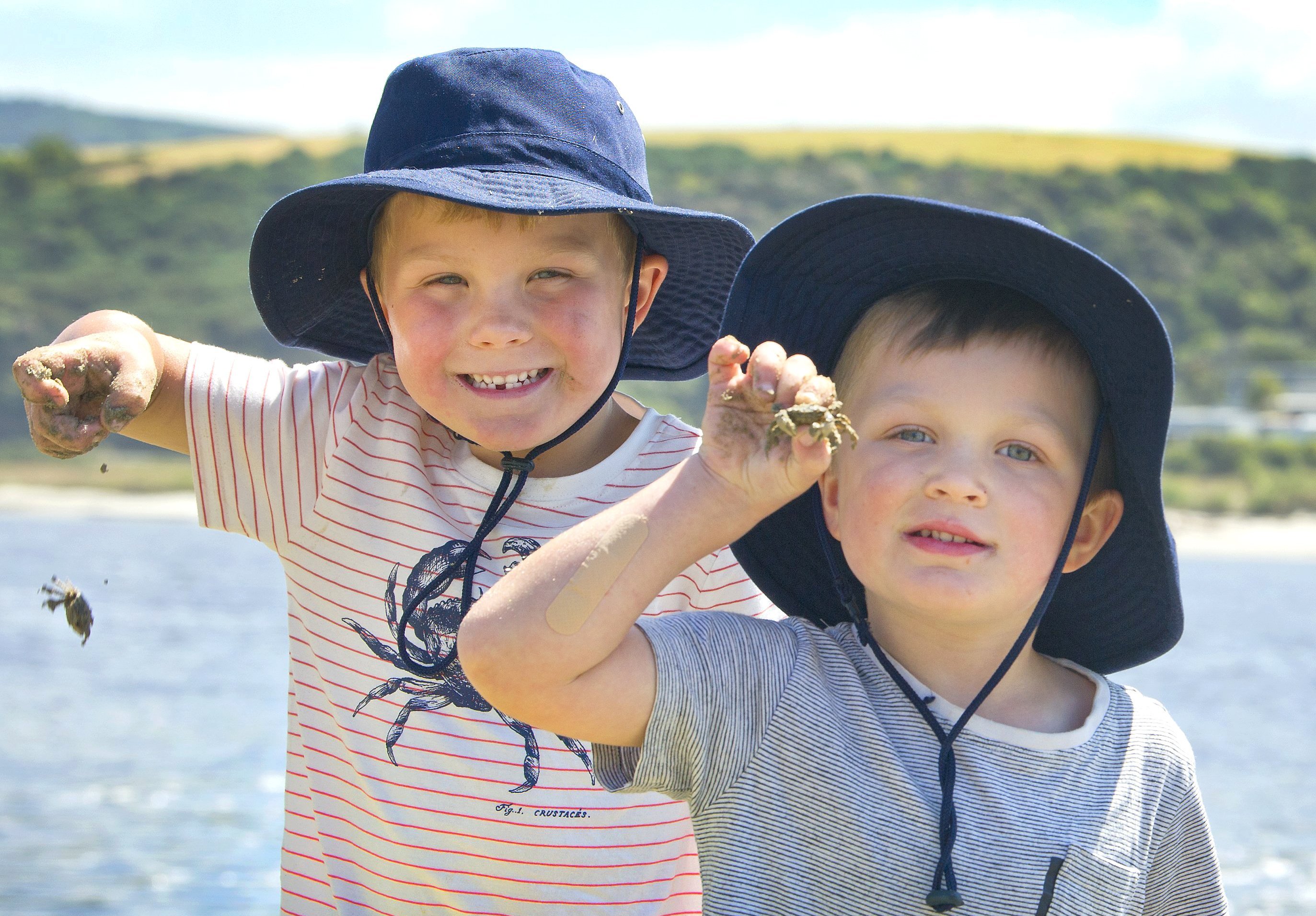 Brothers Hudson (6, left) and Harvey (4) Sides show off the small crabs they caught while playing...