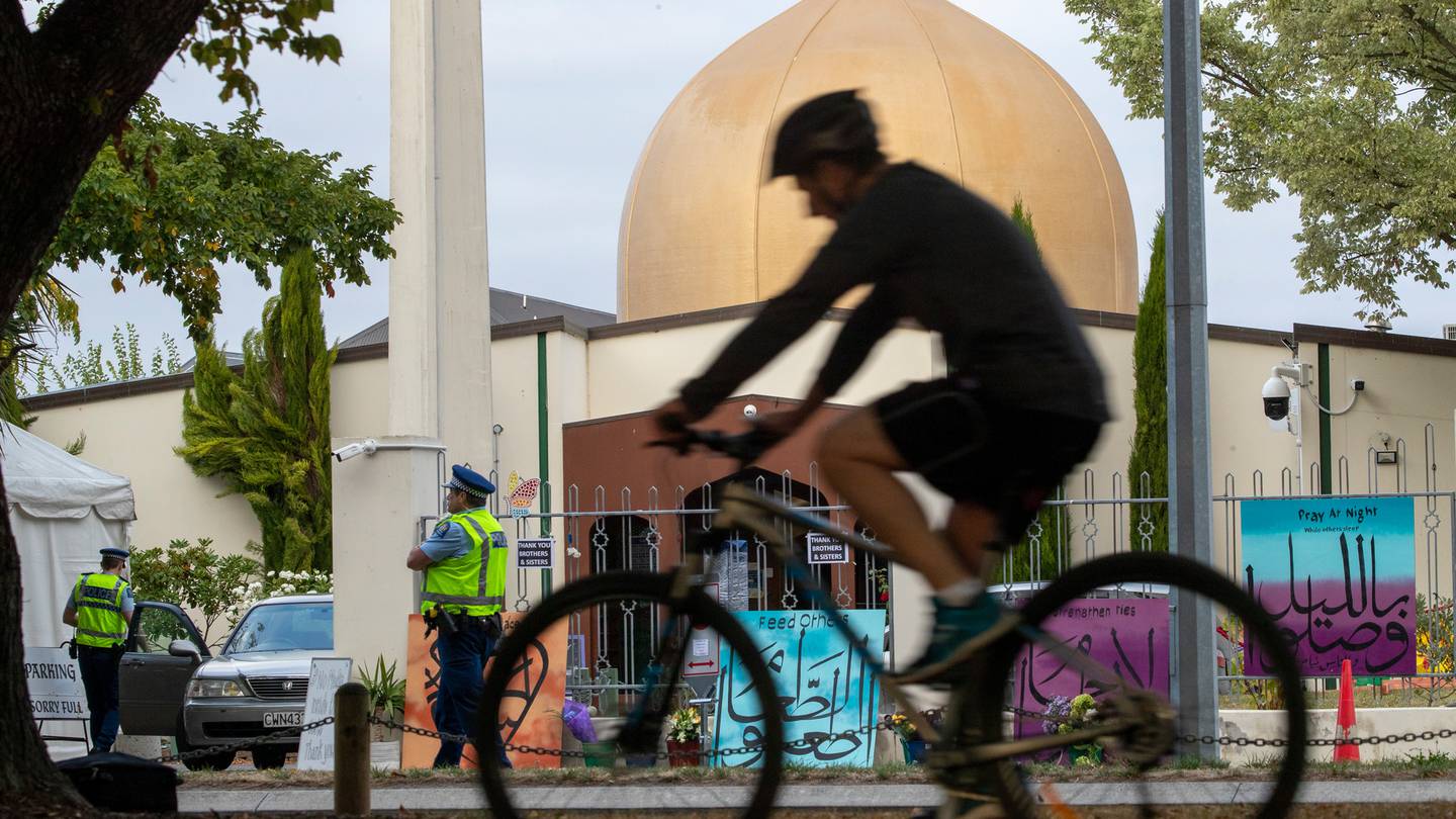 A cyclist rides past police officers keeping watch at Al Noor mosque in Christchurch on the first...
