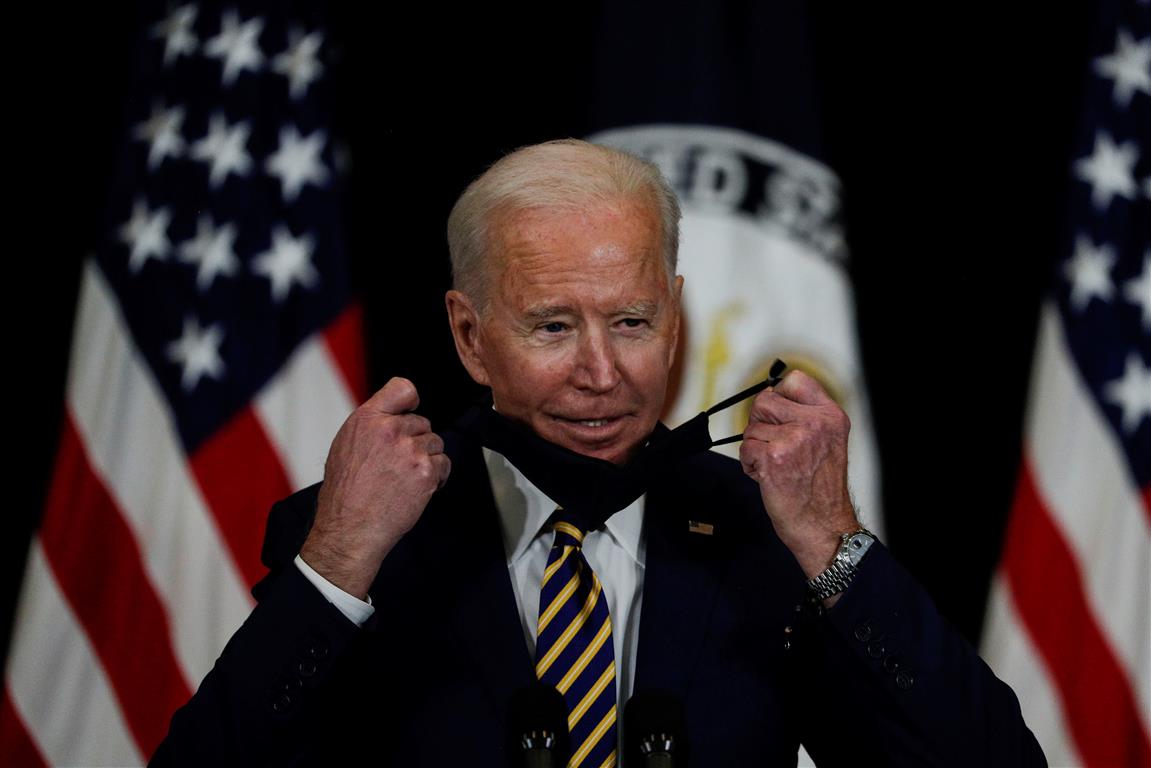 US President Joe Biden removes his mask to speak to staff during a visit to the State Department...