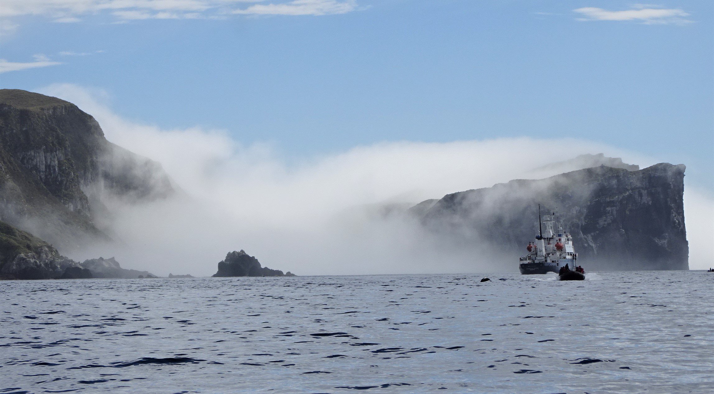 The Antipodes Islands emerge from a sea fog and The Spirit of Enderby  anchored in its waters. ...