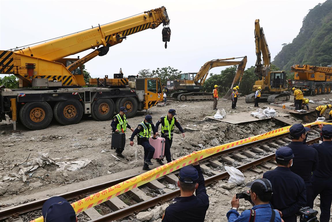 Police officers move passengers' belongings from the site a day after the deadly train derailment...