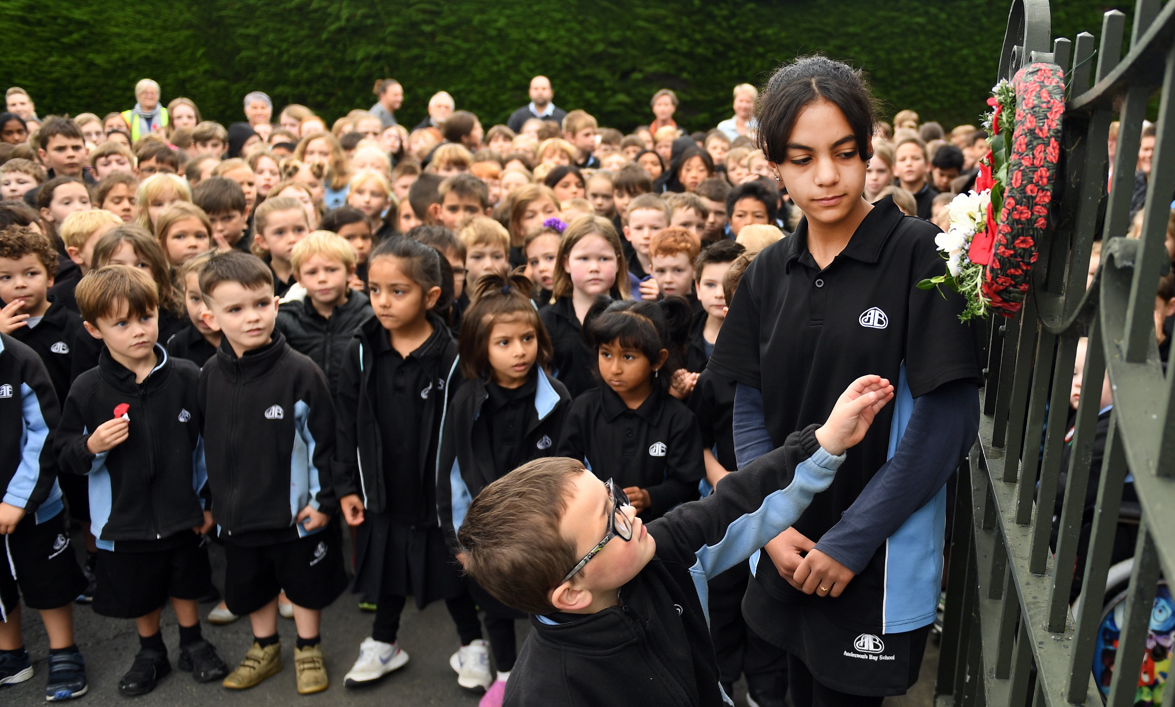 Anderson’s Bay School pupils Sidney Austin (5) and Joulia Dibo (10) place a wreath on the school...