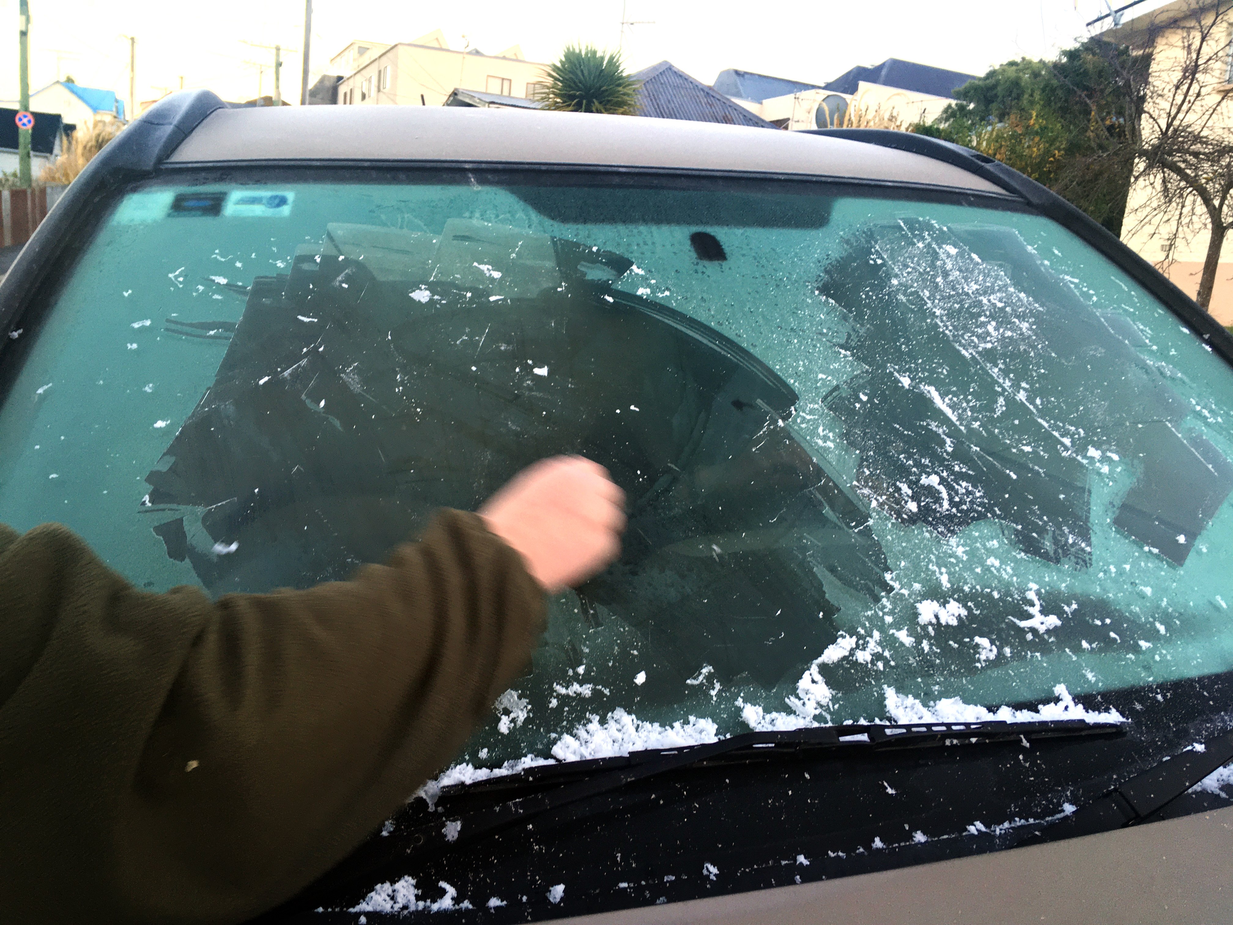 A man scrapes ice from his car window, in Dunedin, yesterday morning, when temperatures dropped...
