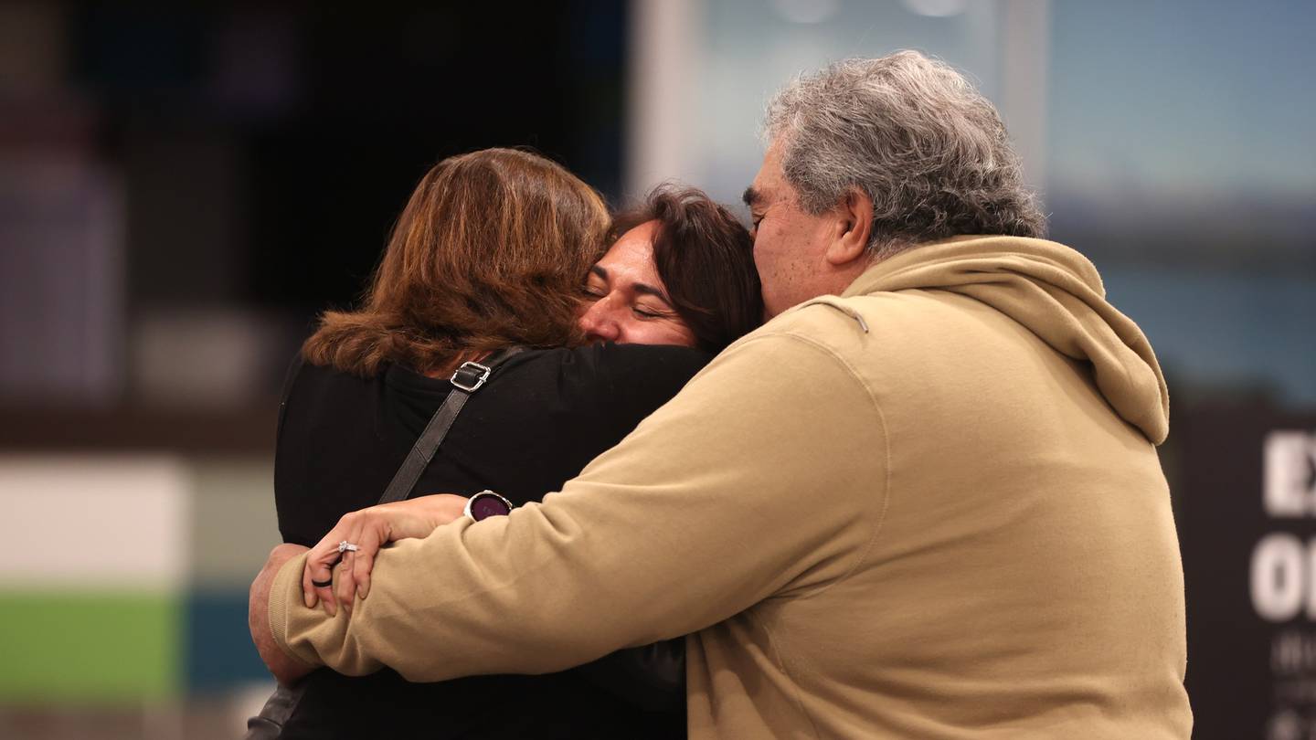 Jonathan and Carol Penfold hug their daughter Alice at Christchurch Airport. Photo: George Heard