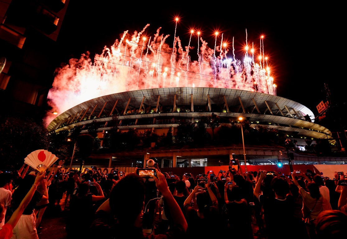 A crowd watches the fireworks display from outside the stadium during the Opening Ceremony for...