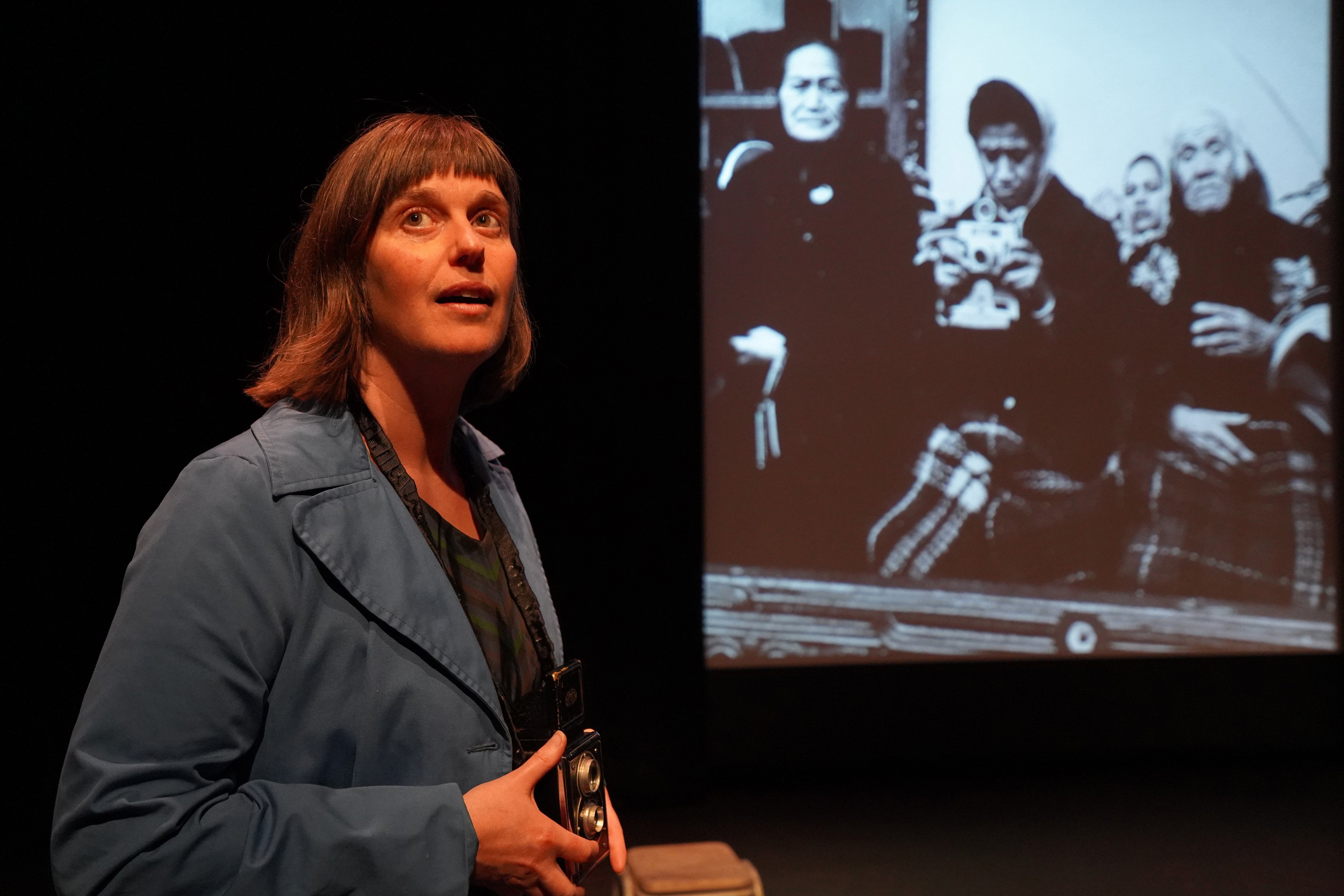 Martine Baanvinger performs as photographer Ans Westra in front of a backdrop of Westra’s images...