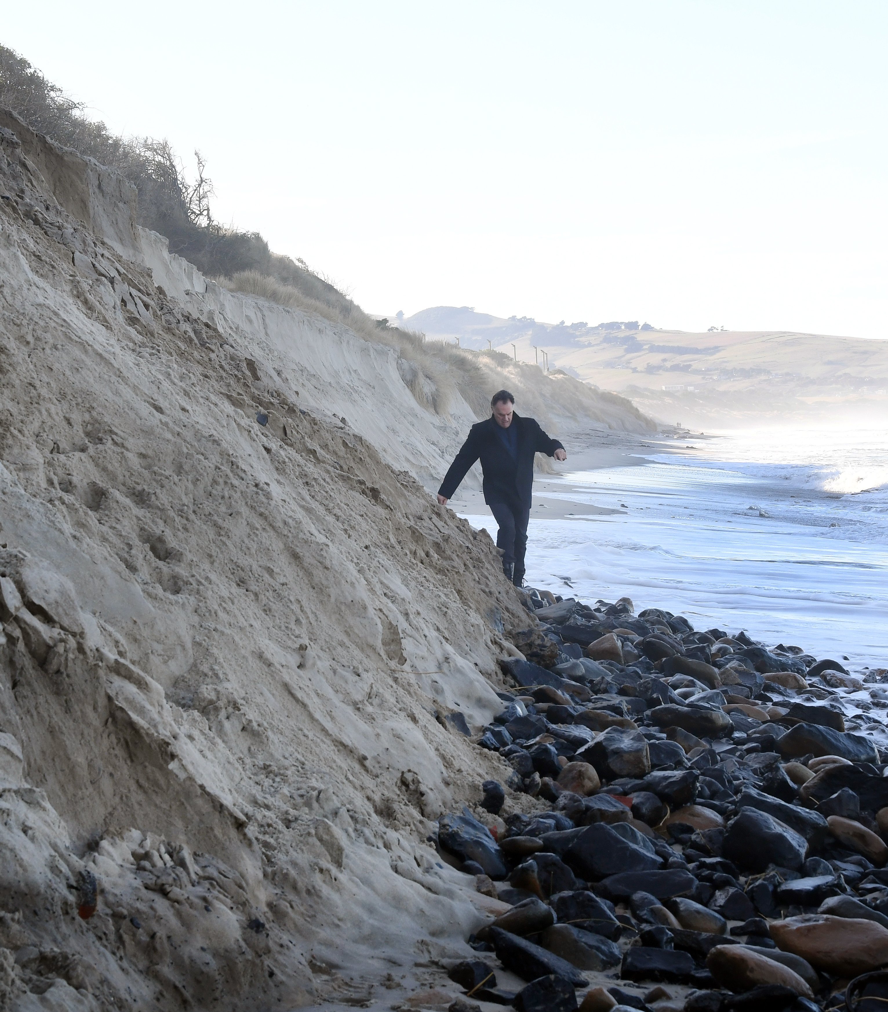 Dunedin city councillor Jules Radich picks his way past rocks exposed by winter erosion at Middle...