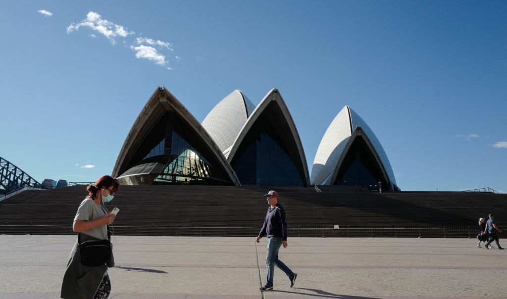 People exercise at a distance from reach other beside the forecourt of the Sydney Opera House during the city's lockdown, which is in place until at least August 28. Photo: Getty