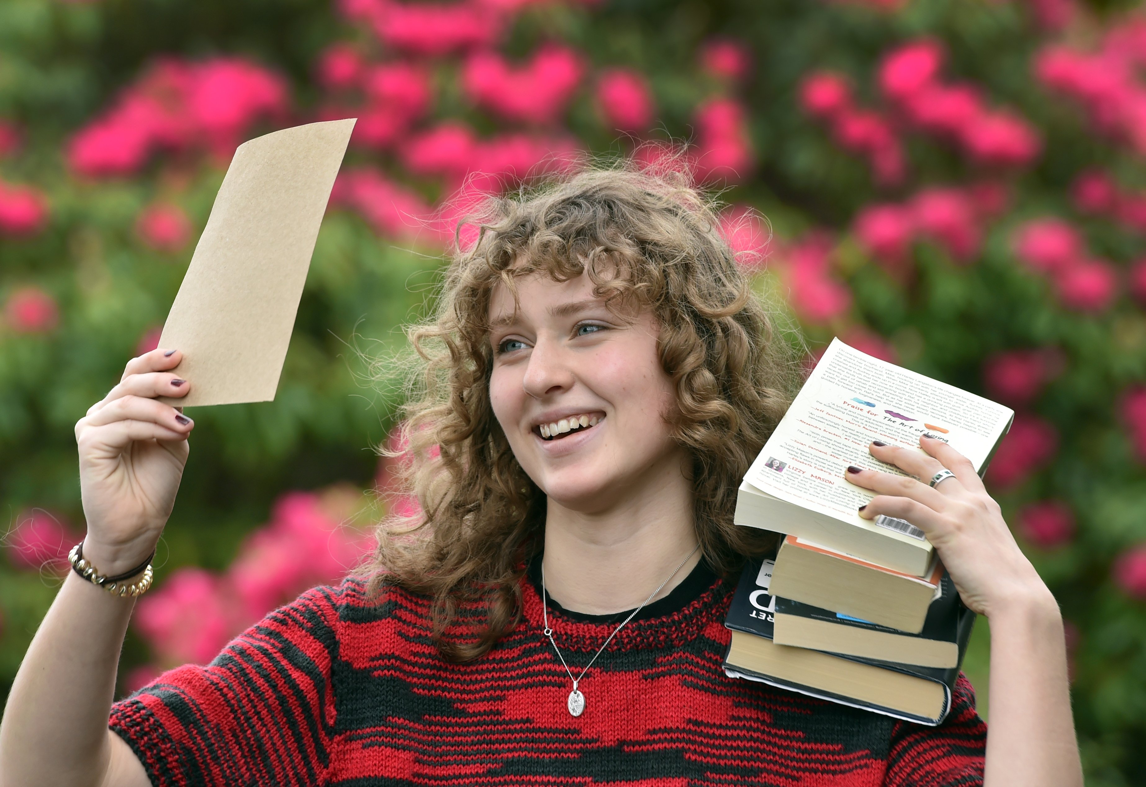 Holding up some of her work and a stack of literary influences is National Schools Poetry Award...