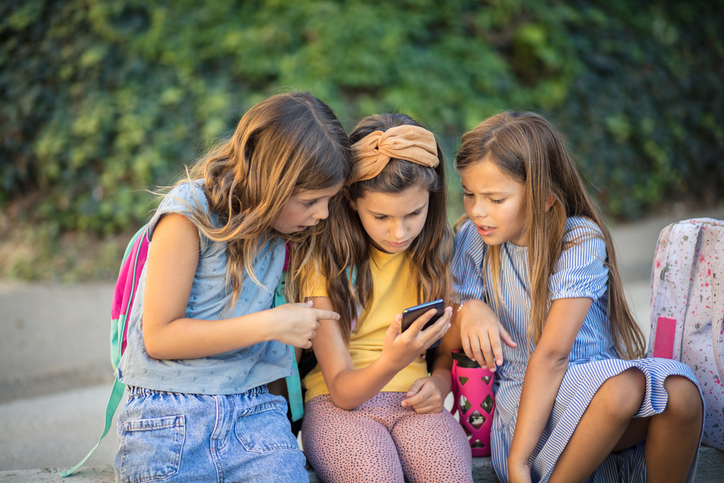 three girls looking at phone getty