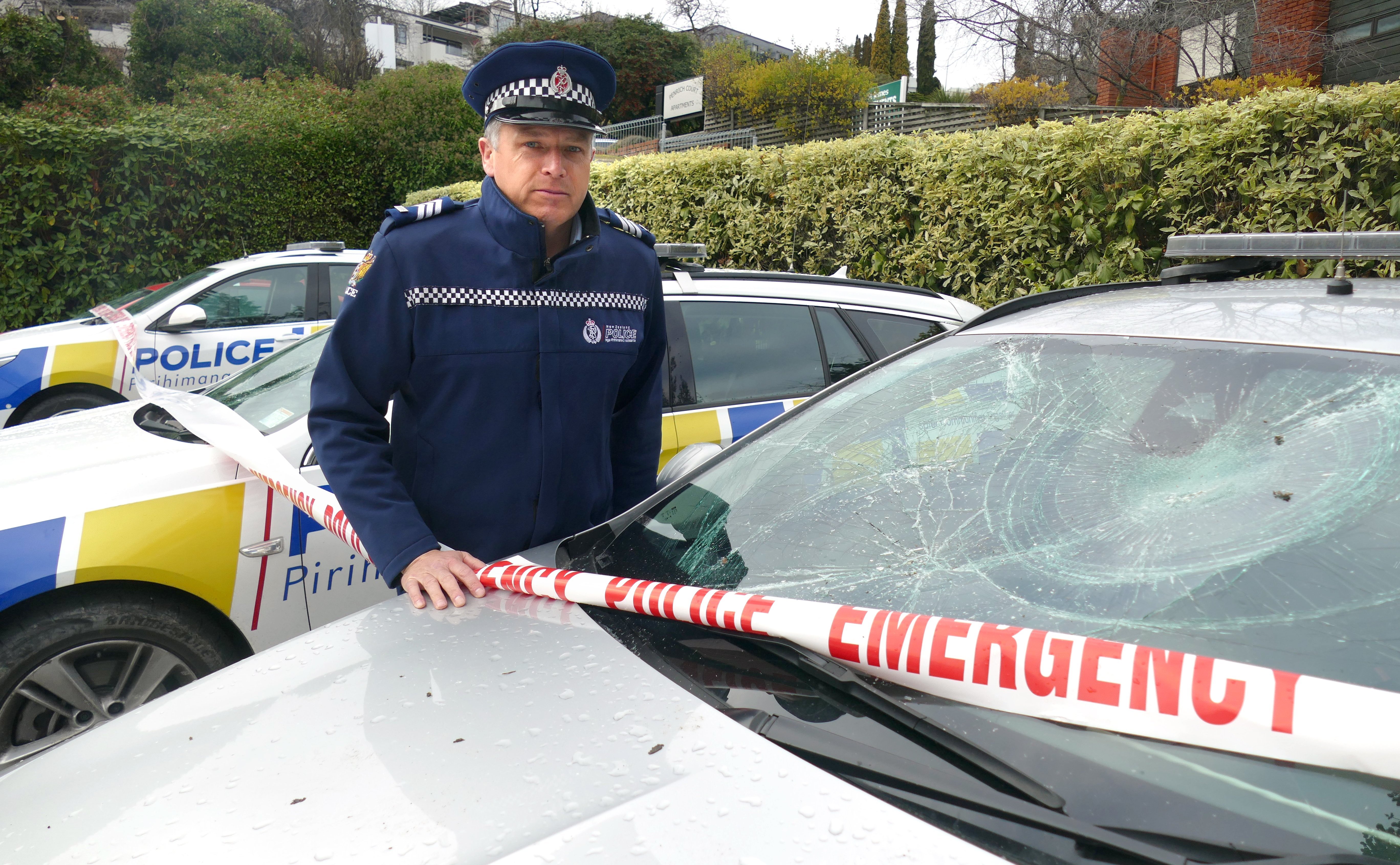 Sergeant Simon Matheson, of Queenstown, with some of the police patrol vehicles damaged in July....