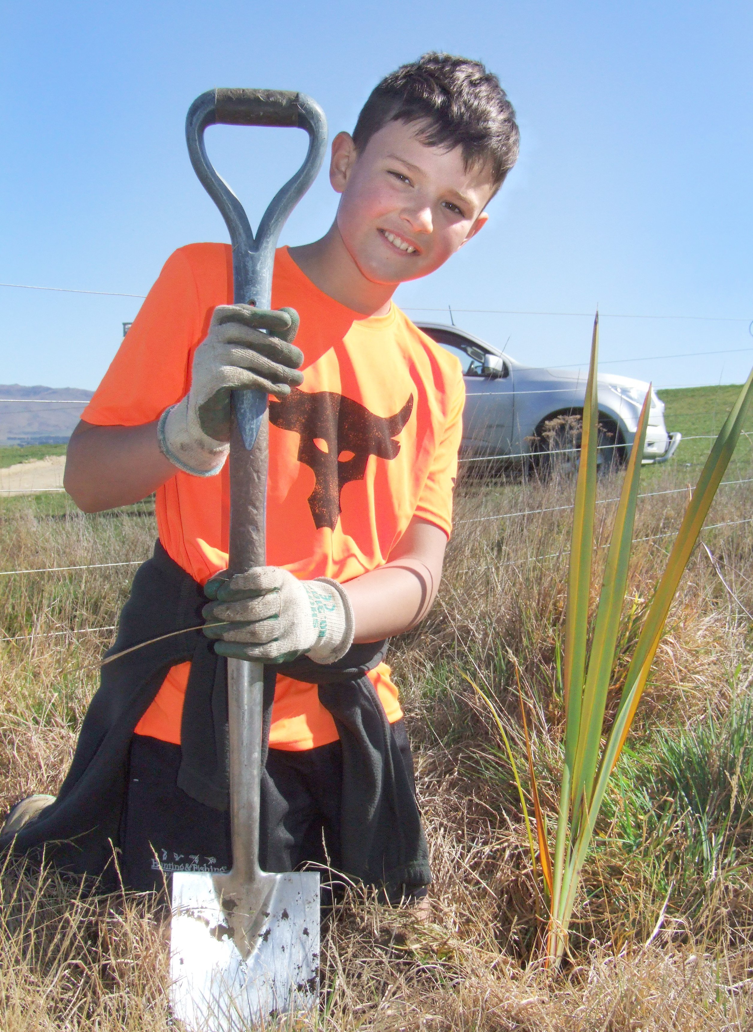 Eddie Weir (10), from Waipiata, plants the first native plant in a trial area for the Tiaki...